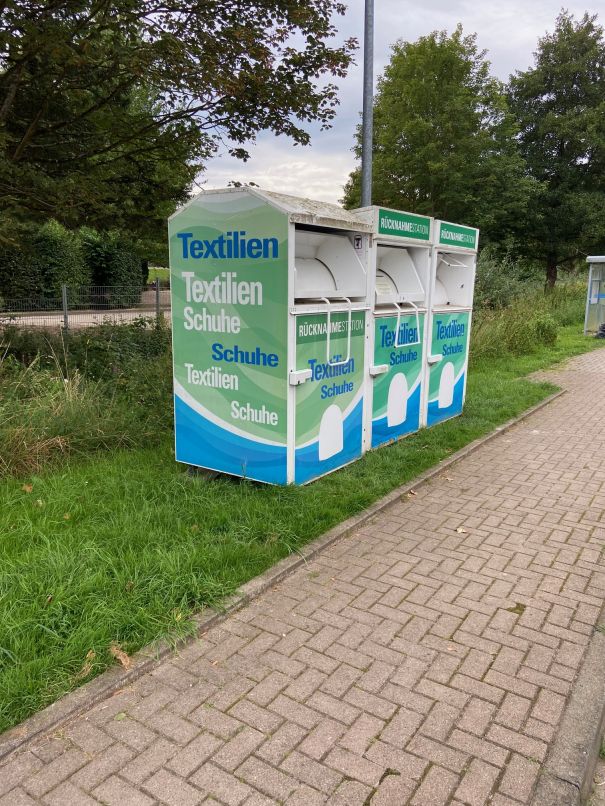 Müllmann zieht ein altes Ledersofa auf dem eine junge Frau entspannt auf Ihr Tablet schaut.