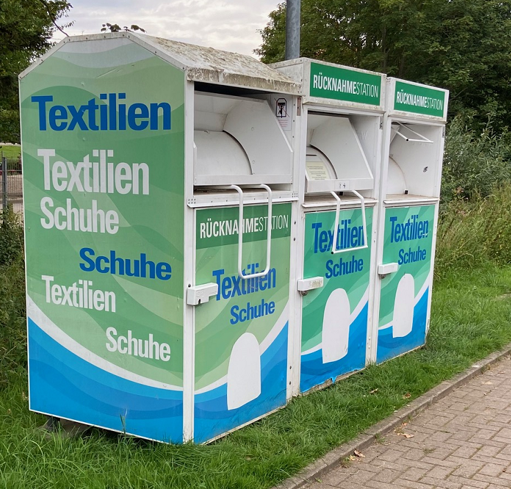 Müllmann zieht ein altes Ledersofa auf dem eine junge Frau entspannt auf Ihr Tablet schaut.